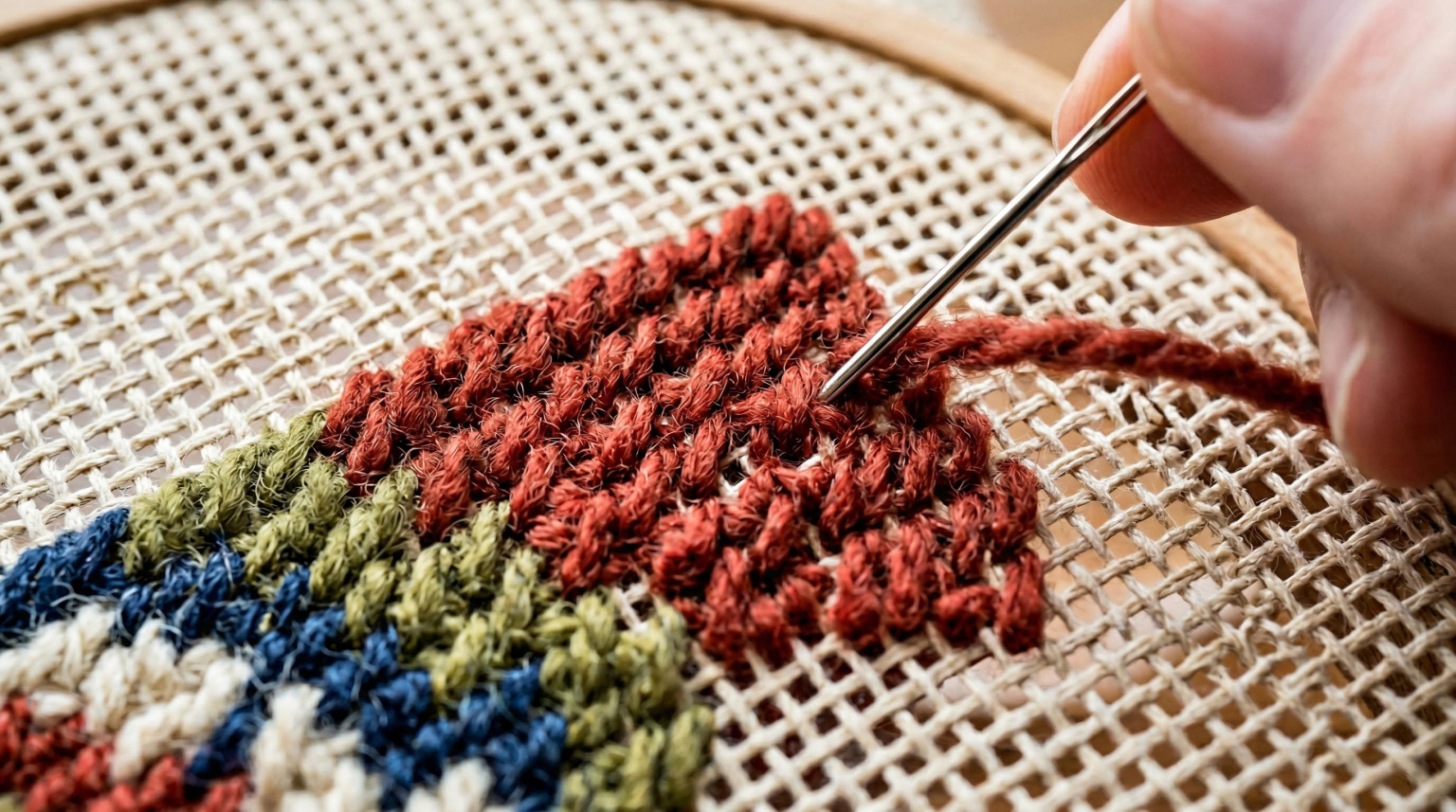 Close-up of needlepoint stitching on canvas showing detailed wool tent stitches
